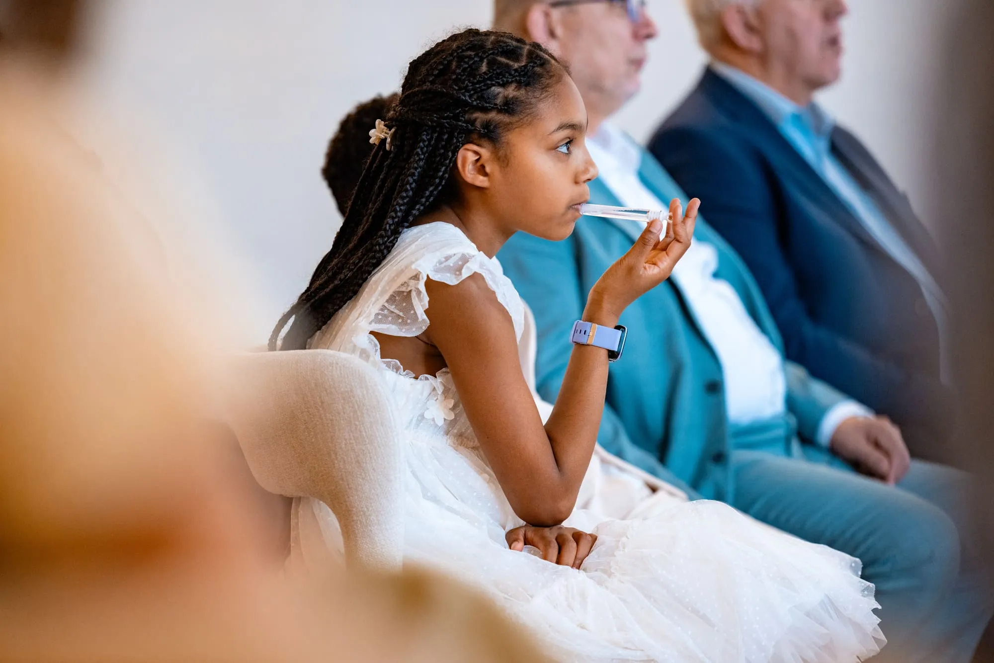 Een bruidsmeisje in een witte jurk kijkt aandachtig toe tijdens de ceremonie
