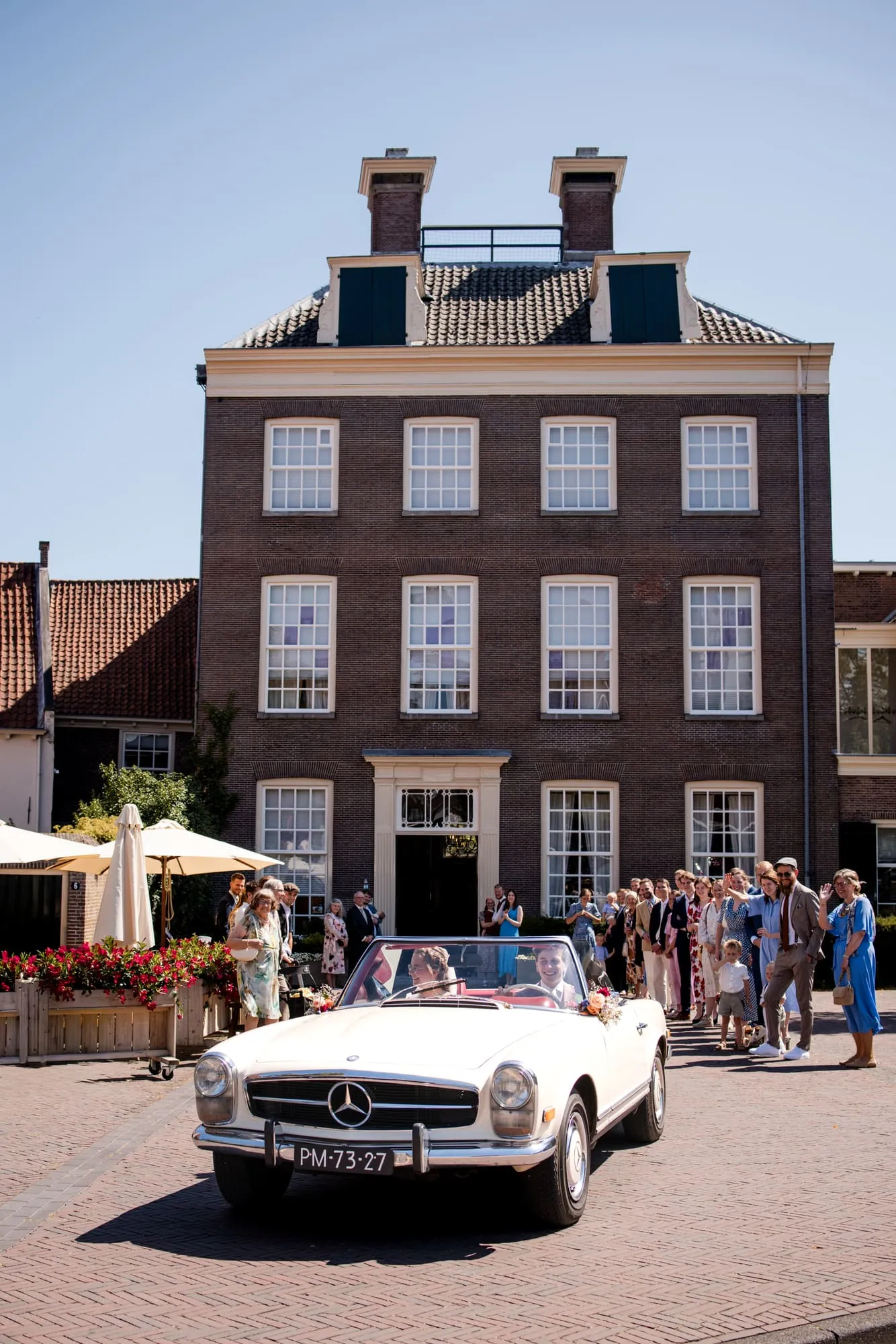Gasten wachten met een klassieke Mercedes voor het huis van het bruidspaar